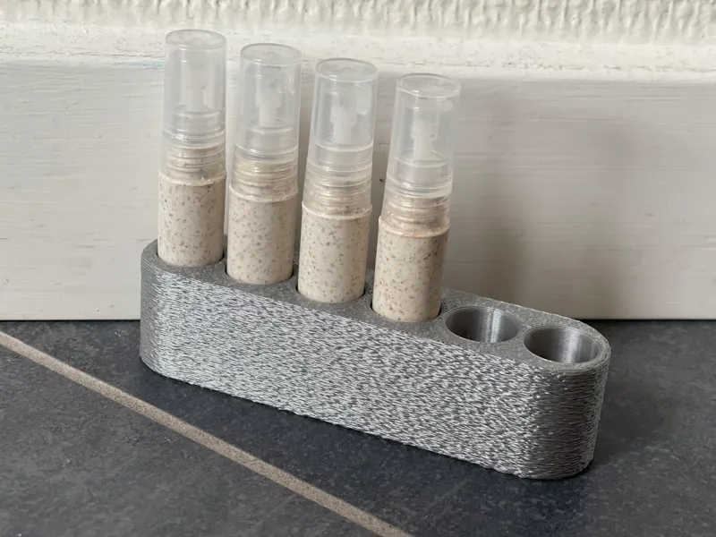 Printed stand holding four perfume sample vials